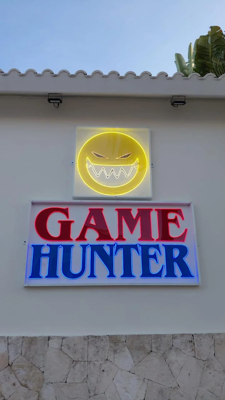 Logo GAME HUNTER en neón amarillo sobre fachada blanca