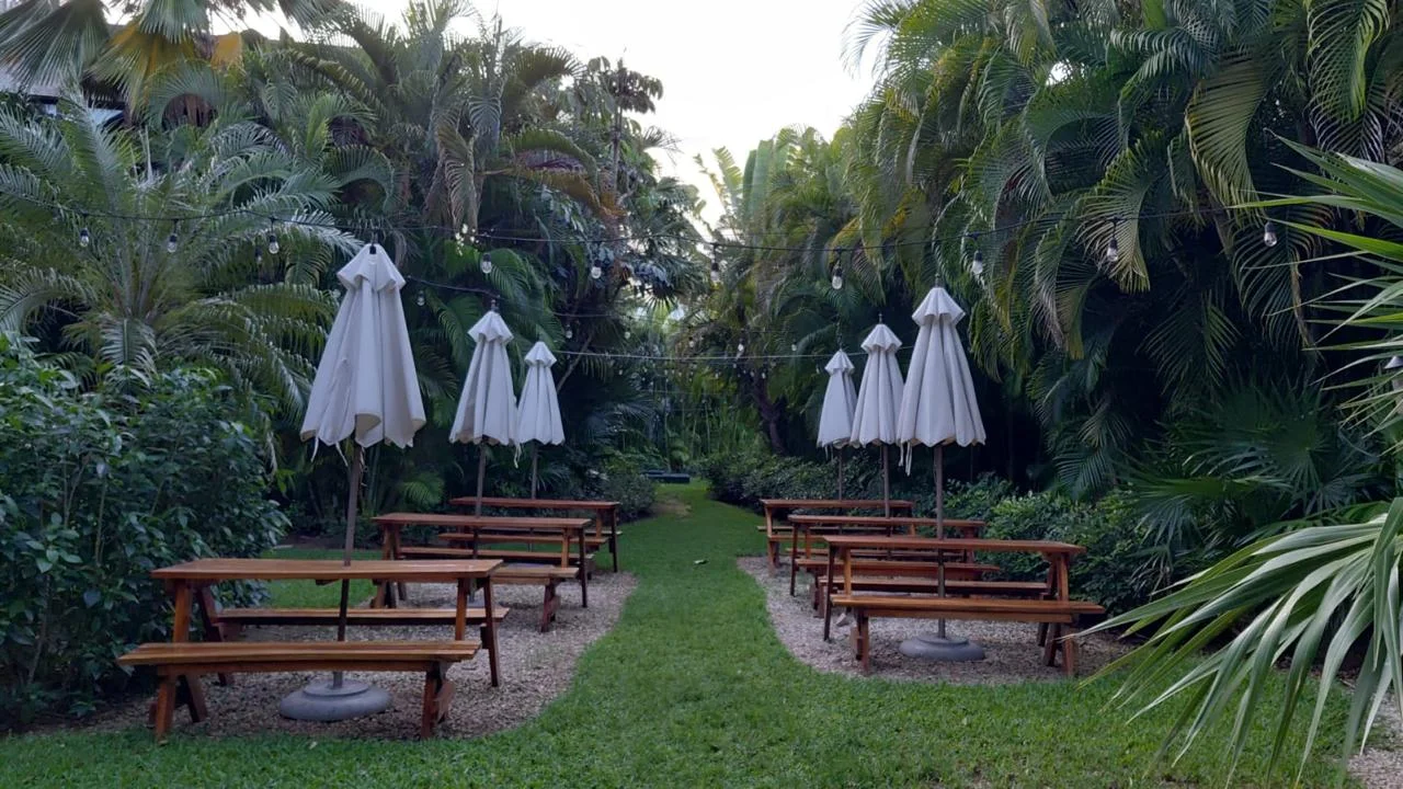 Jardín tropical con mesas, bancos y sombrillas para eventos