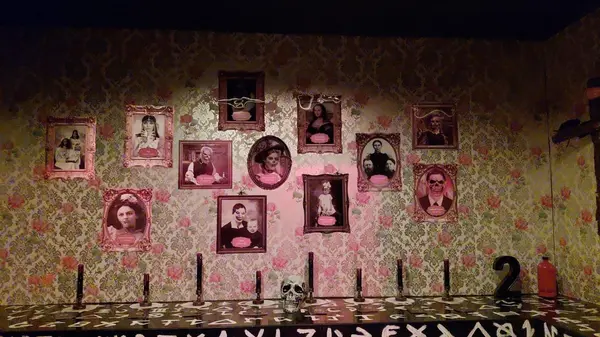 Sala Escape Room temática Familia Addams con retratos y mesa Ouija